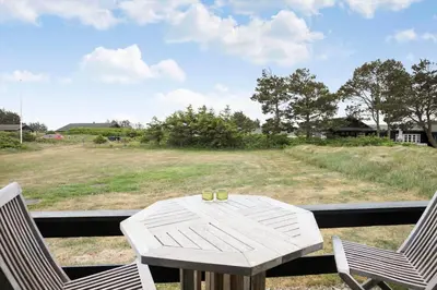 a table and chairs on a porch with a view of a field at LK1955-Lokken-Laurasvej-10 in Løkken