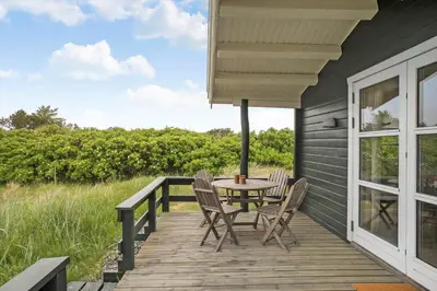 a wooden deck with a table and chairs on a house at LK1955-Lokken-Laurasvej-10 in Løkken