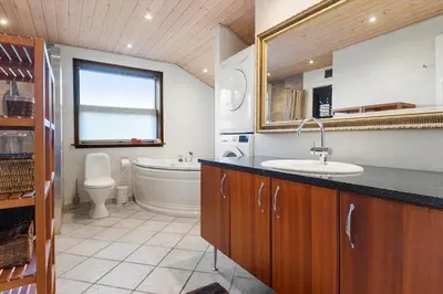 a bathroom with a sink and a toilet and a mirror at LK933-Lokken-Olgavej-34 in Løkken