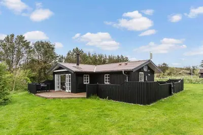 a black house with a fence in a field at LK2029-Lokken-Magdalenevej-55 in Løkken