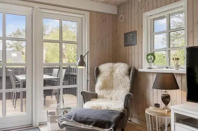a living room with a chair and a sliding glass door at LK2029-Lokken-Magdalenevej-55 in Løkken