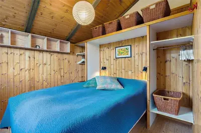 a bedroom with a blue bed in a wooden wall at LK1709-Lokken-Ruthsvej-12 in Løkken