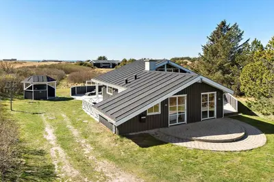 a house with a gambrel roof on a grass field at LK855-Lokken-Monasvej-7 in Løkken