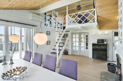 a kitchen and dining room with a loft bed and purple chairs at LK855-Lokken-Monasvej-7 in Løkken
