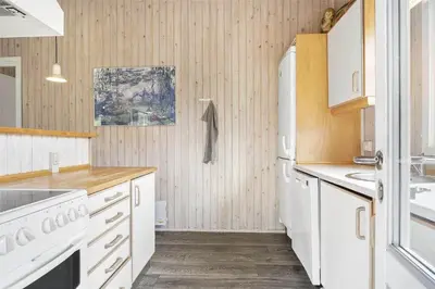 a kitchen with white appliances and wooden walls at LK1221-Lokken-Louisevej-5 in Løkken