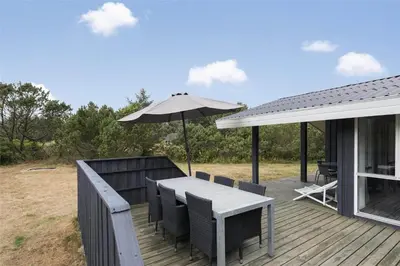 a wooden deck with a table and an umbrella at LK1221-Lokken-Louisevej-5 in Løkken