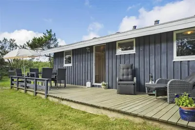 a house with a wooden deck with a table and chairs at LK1221-Lokken-Louisevej-5 in Løkken