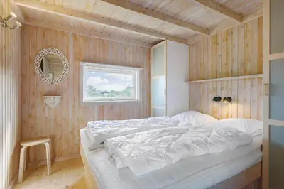 a bedroom with a white bed in a wooden wall at LK850-Lokken-Jorginesvej-8 in Løkken