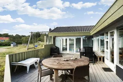 a wooden deck with a table and chairs on a house at LK850-Lokken-Jorginesvej-8 in Løkken
