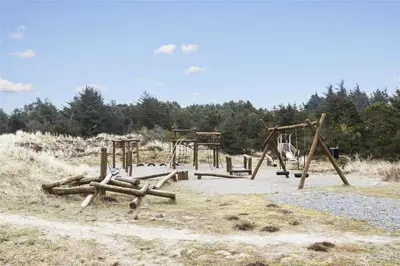 a playground with wooden swings and logs in a field at BL1478-Blokhus-Ferren-Syd-152 in Blokhus