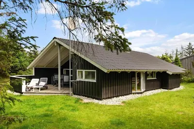 a black cottage with a deck and two chairs at LK599-Lokken-Stellavej-16 in Løkken