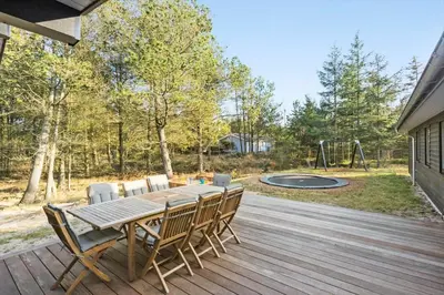 a wooden table and chairs on a deck with a playground at BL1535-Blokhus-Saetergaardsstien-5-A in Blokhus