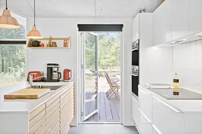 a kitchen with white cabinets and a door leading to a patio at BL1535-Blokhus-Saetergaardsstien-5-A in Blokhus