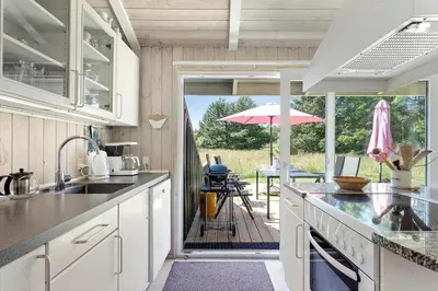 a kitchen with a view of a patio with an umbrella at BL102-Saltum-Kvansletten-13 in Saltum