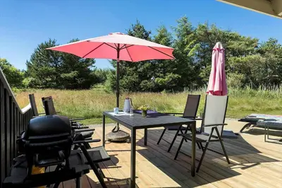 a patio with a table and an umbrella and chairs at BL102-Saltum-Kvansletten-13 in Saltum