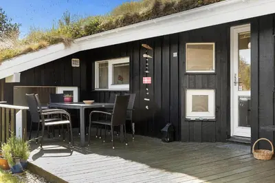 a black house with a table and chairs on a deck at BL102-Saltum-Kvansletten-13 in Saltum
