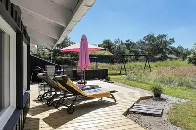 a patio with a chair and an umbrella on a deck at BL102-Saltum-Kvansletten-13 in Saltum