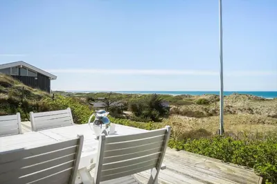 a white table with chairs and the ocean in the background at LK1990-Lokken-Lottesvej-27 in Løkken