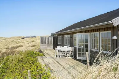 a house with a deck and chairs on the beach at LK1990-Lokken-Lottesvej-27 in Løkken