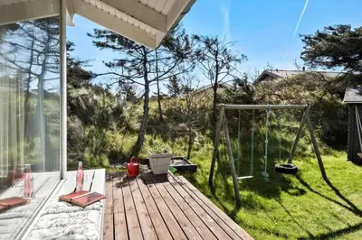 a wooden deck with a swing and a yard at BL124-Blokhus-Klitvejen-75-a in Blokhus