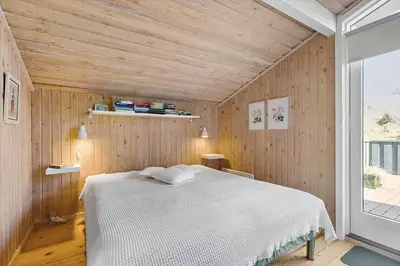 a bedroom with a white bed in a wooden wall at BL124-Blokhus-Klitvejen-75-a in Blokhus