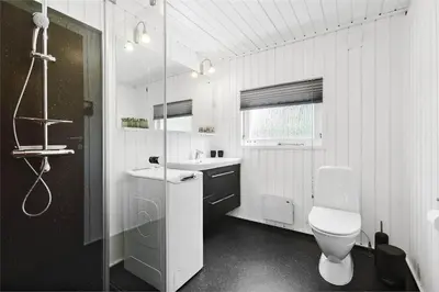 a white bathroom with a toilet and a sink at BL1402-Blokhus-Bag-Hojen-57 in Blokhus