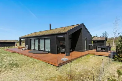 a black house with a deck in a field at BL1642-Saltum-Bondagervej-50 in Saltum