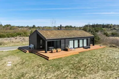 a black house with a deck in a field at BL1642-Saltum-Bondagervej-50 in Saltum