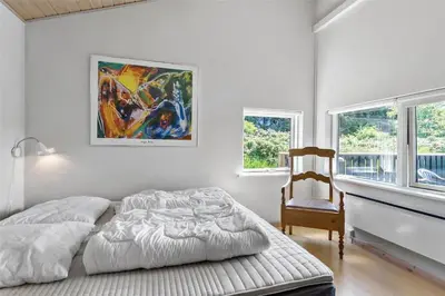 a bedroom with a bed and a chair and a painting at LK1813-Lokken-Jorginesvej-3 in Løkken