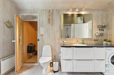 a bathroom with a toilet and a sink and a mirror at BL368-Blokhus-Bag-Hojen-19 in Blokhus