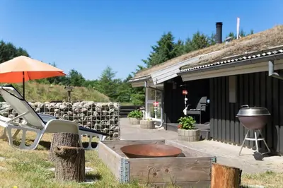 a patio with a grill and a chair and an umbrella at BL368-Blokhus-Bag-Hojen-19 in Blokhus