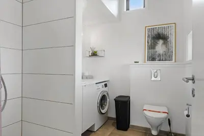 a white bathroom with a washing machine in it at BL1635-Blokhus-Lyngdraget-19 in Blokhus