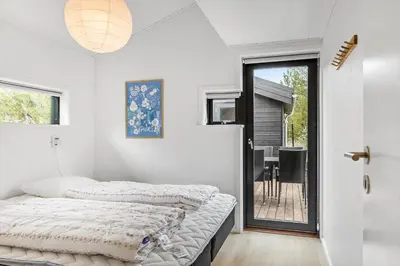 a white bedroom with a bed and a balcony at BL1635-Blokhus-Lyngdraget-19 in Blokhus