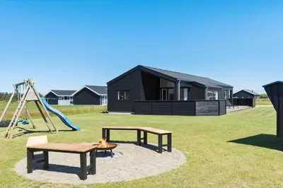 a black house with a playground and a swing at LK2031-Lokken-Kringelbaekvej-55 in Løkken