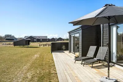 a couple of chairs and an umbrella on a deck at LK2031-Lokken-Kringelbaekvej-55 in Løkken