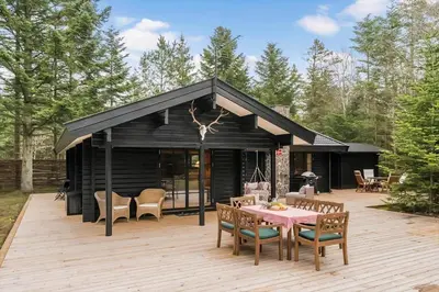 a black cabin with a table and chairs on a deck at BL1224-Saltum-Vikingebanke-7 in Saltum