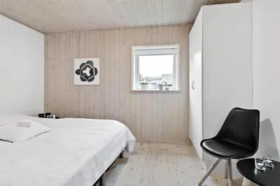 a bedroom with a white bed and a black chair at BL1629-Blokhus-Klitgaardsvej-29 in Blokhus