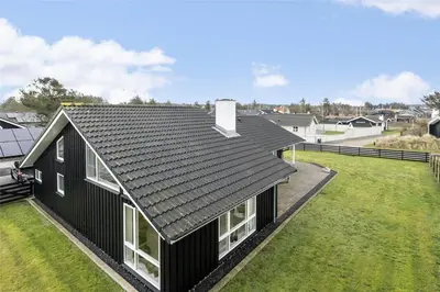 an aerial view of a black house with a yard at BL1629-Blokhus-Klitgaardsvej-29 in Blokhus