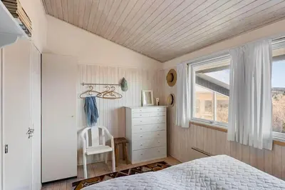 a bedroom with a bed and a chair and a window at BL1265-Saltum-Faaborgvej-7 in Saltum