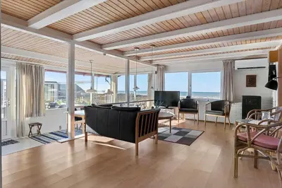 a living room with a table and chairs and windows at LK2130-Lokken-Lottesvej-23 in Løkken