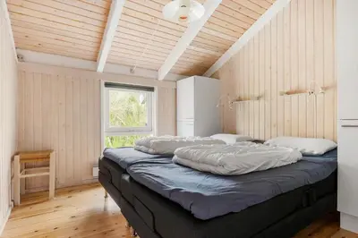 a large bed in a room with wooden walls at BL416-Saltum-Revlingevej-28 in Saltum
