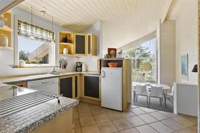 a kitchen with a white refrigerator and a table at BL547-Blokhus-Skraavejen-8 in Blokhus