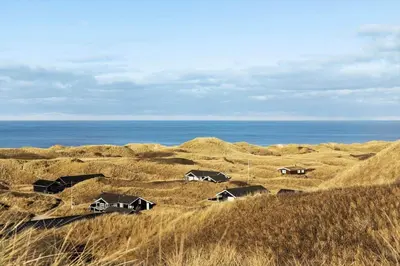 a group of houses in a field with the ocean at LK2117-Lokken-Kettrup-Bjerge-Vej-55 in Løkken