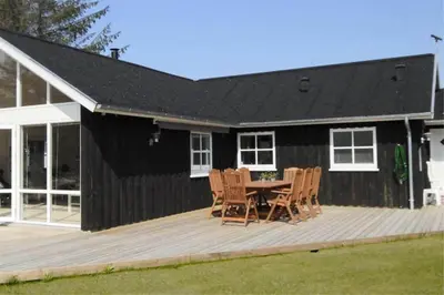 a black house with a table and chairs on a deck at BL704-Blokhus-Soren-Petersvej-7 in Blokhus