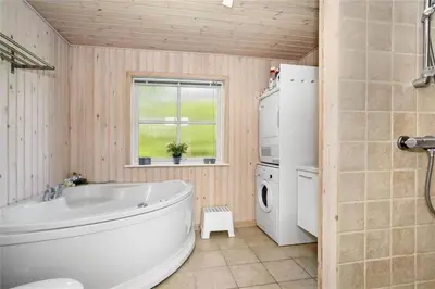 a bathroom with a tub and a washing machine at BL704-Blokhus-Soren-Petersvej-7 in Blokhus