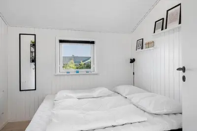a white bedroom with a large bed with a window at LK2141-Lokken-Kristavej-15 in Løkken