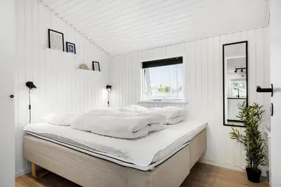 a bedroom with a bed with white sheets and a window at LK2141-Lokken-Kristavej-15 in Løkken