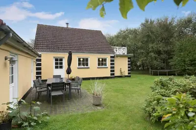 a house with a table and chairs in a yard at BL367-Pandrup-Rodhus-Kirkevej-5 in Pandrup