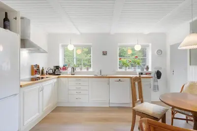a kitchen with white cabinets and a wooden table at BL367-Pandrup-Rodhus-Kirkevej-5 in Pandrup