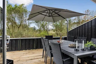 a table and chairs with an umbrella on a deck at LK2126-Lokken-Jorginesvej-4 in Løkken